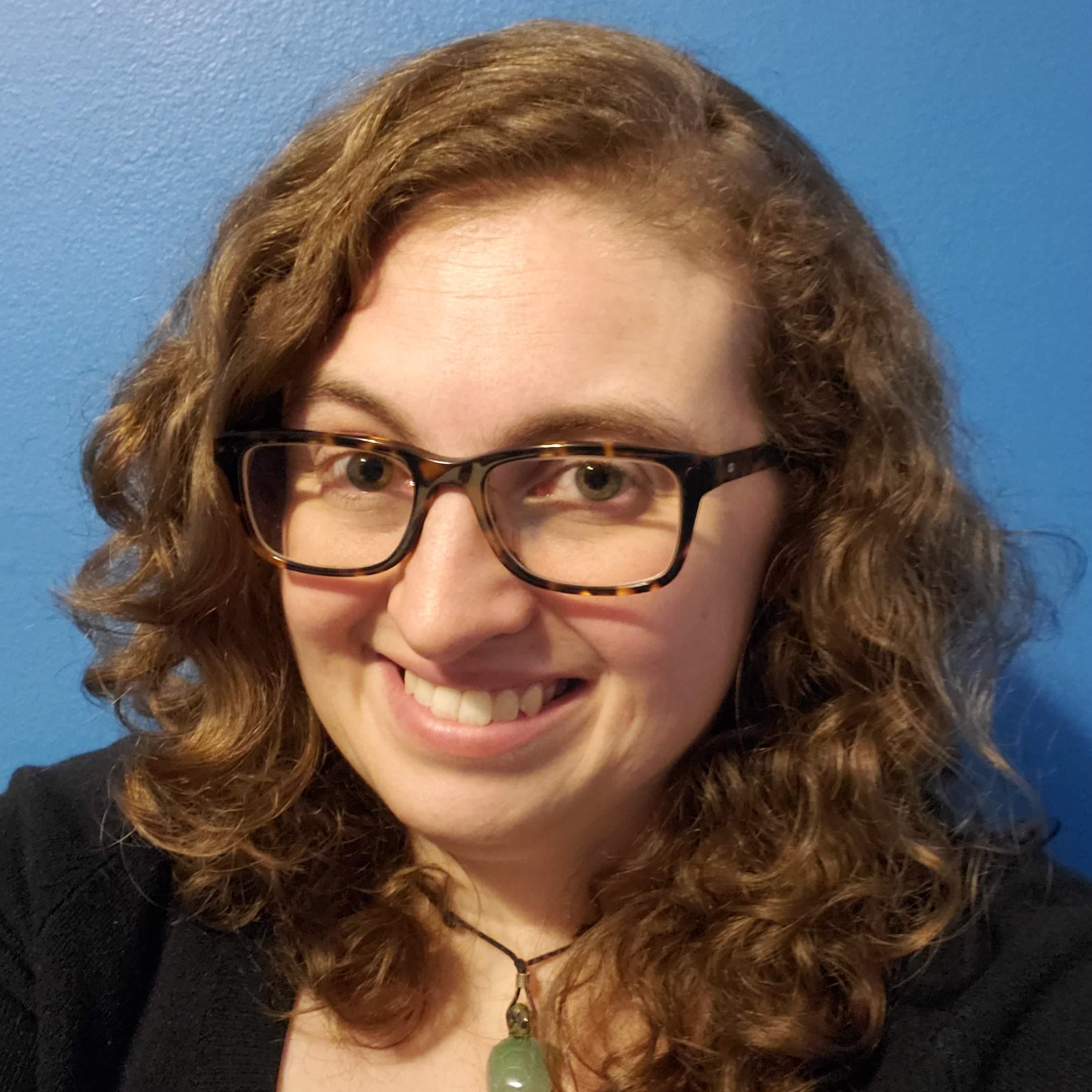 Jen Bauer's headshot picture, which shows a curly-haired brunette with glasses and a winning smile.
